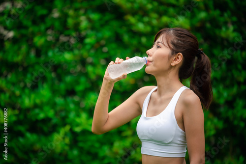 Asian young woman drinking water after workout exercising.