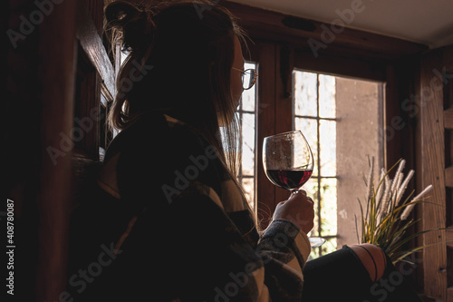 Relaxed woman at the window with glass of wine