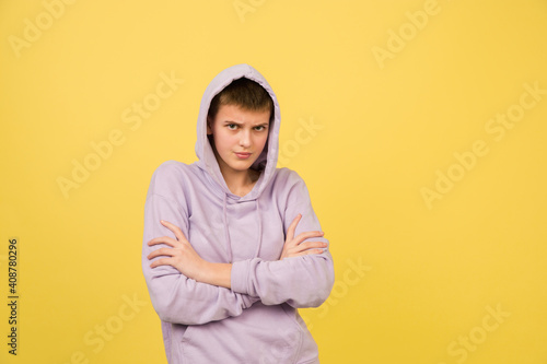 Looks offended, hands crossed. Caucasian girl's portrait isolated on yellow background with copyspace. Beautiful female model in hoodie. Concept of human emotions, facial expression, sales, ad © master1305