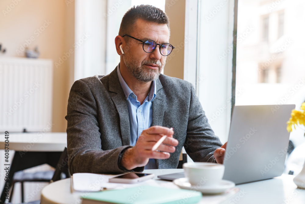Obraz premium Handsome confident businessman working on laptop