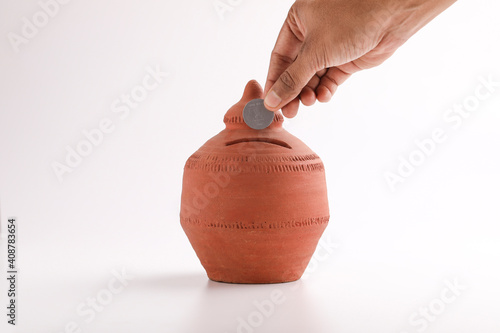 putting a coin into a clay money box: investments, retirement fund and banking concept photo