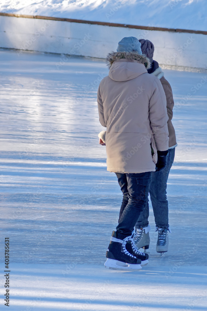 A guy and a girl skate on the ice  on a cold winter day