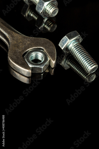 Wrench with nut and bolt on black background. The idea of connecting spare parts in construction