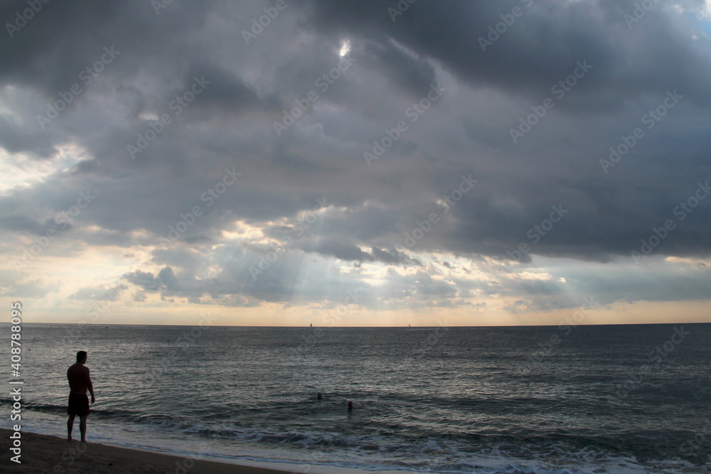 alone man on the beach. Storm weather on the sea. Dramatic view. grey clouds over the sea. summer sunset