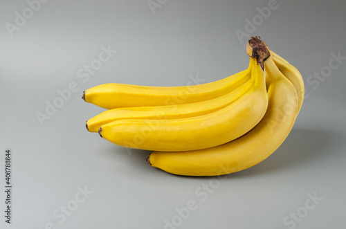 Bunch of bananas on a gray background. Trending color Pantone of year 2021 Illuminating and Ultimate gray. Side view minimal still life.