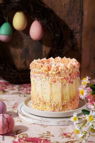 Beautiful composition with Easter fun cake decorated with sprinkles on a wooden background with space for text. Romantic vintage style. Spring station concept.