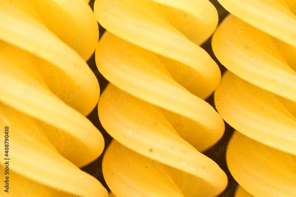 Several bright yellow Fusilli pasta on a slate board, close-up, top view.
