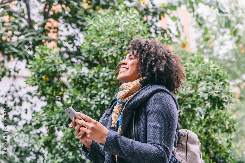 African American woman smiled while reading her mobile phone on a cold day African American woman smiled while reading her mobile phone on a cold day