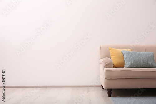 Fototapeta Naklejka Na Ścianę i Meble -  Comfortable beige sofa near light wall indoors, space for text. Simple interior