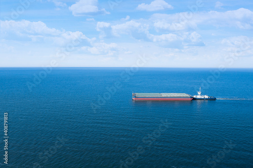 Tugboat pulling barge with cargo by water, aerial view © New Africa