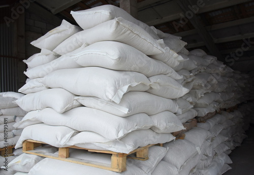Bags of cement are stacked on wooden pallets in the factory warehouse, ready for further transportation.