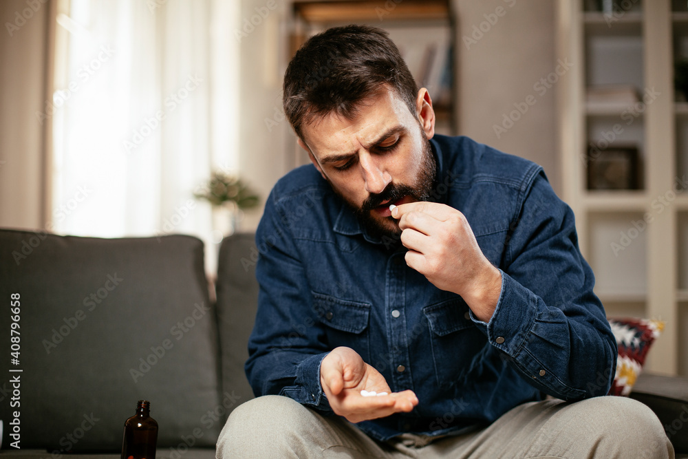 Sick man at home. Young man sitting on sofa having fever. Sick man at home. Young man sitting on sofa having fever.
