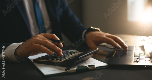 Businessman using calculator and laptop for calculate bills Finances, savings and economy concept. Tax and accounting. 