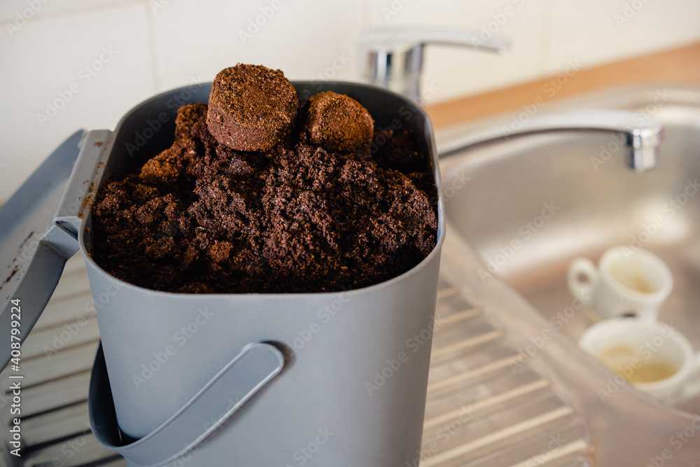 Used coffee grounds from espresso machine. Recycling compost container filled with used coffee