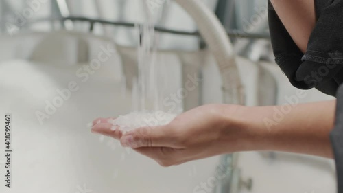 Slowmo close-up of unrecognizable female hands pouring small polypropylene granules at inductrial factory photo