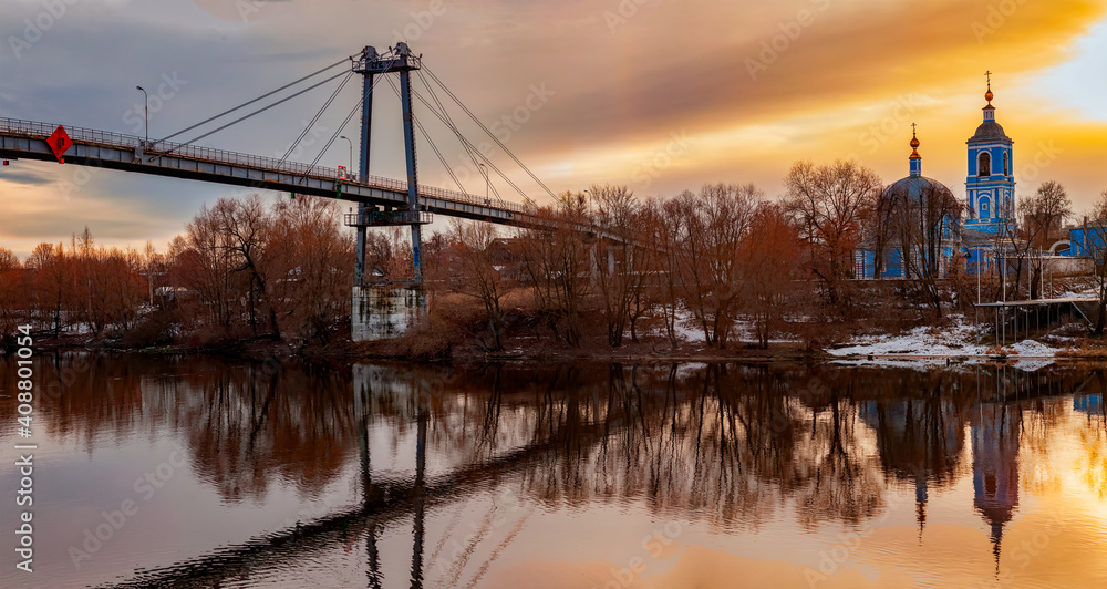 The Church of St. John Chrysostom and the bridge on the bank of the Moskva River at sunset on an autumn day. Autumn rural landscape. Voskresensk, Moscow Region-November 2020