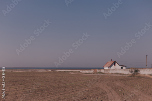 House on the edge of an agronomic field, car wheel tracks