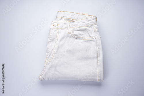 White jeans stacked on a gray background, top view.