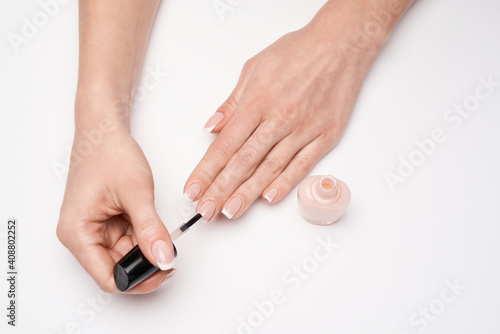 Woman making manicure by herself on grey background