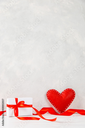 Red heart, gift, ribbon against the background of white wall, concept, a postcard for Valentine's Day. Copy space.