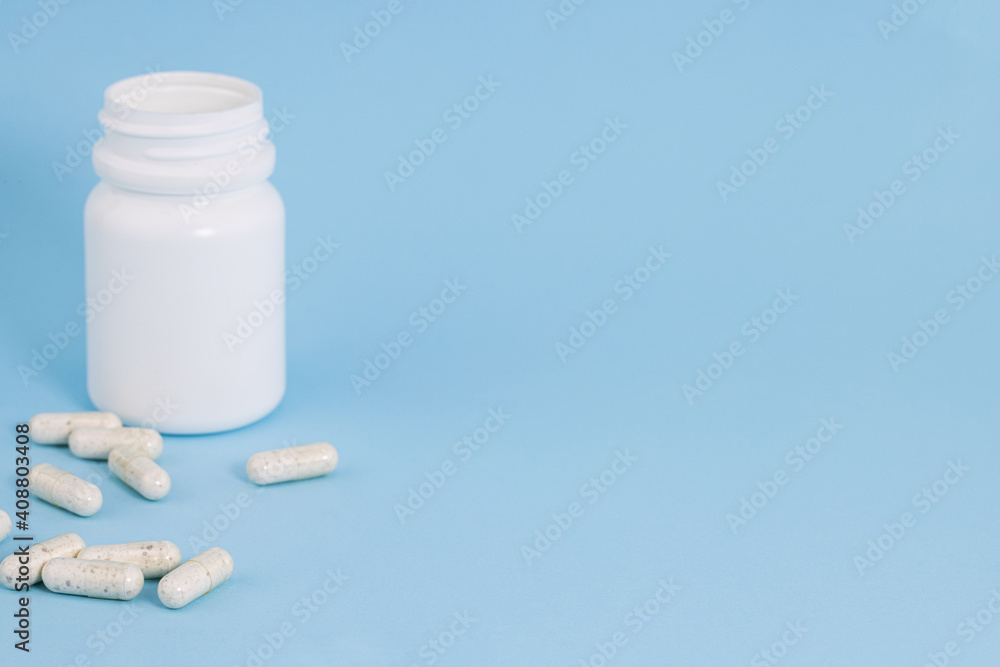 bottle with scattered pills on blue background with copy space bottle with scattered pills on blue background with copy space