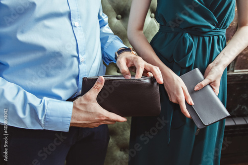 a woman and a man in the interior hold purses in their hands