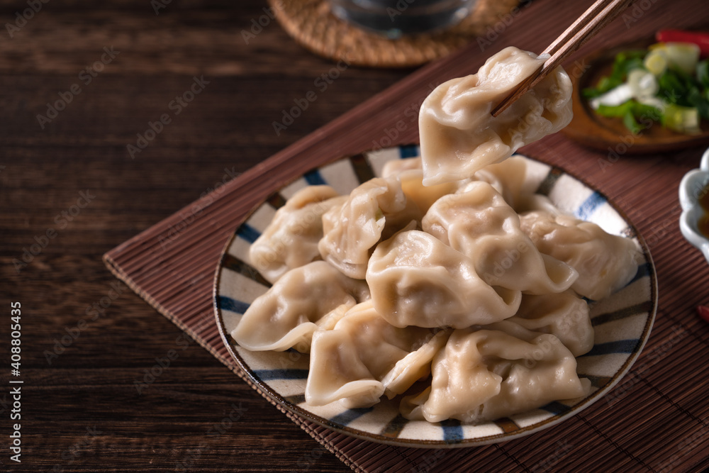 Eating fresh boiled dumpling using chopsticks with soy sauce. Eating fresh boiled dumpling using chopsticks with soy sauce.