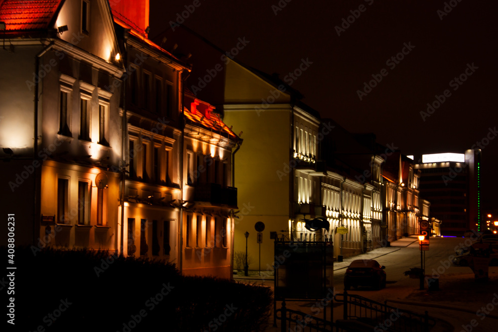 Horizontal cityscape three quarter view photo with facades of buildings in the old part of the city with night illumination on an empty deserted street during winter calm night