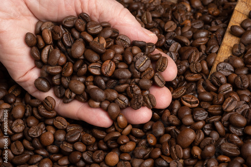 Elderly woman holding coffee beans in hand. Selective focus on coffee beans in hand .