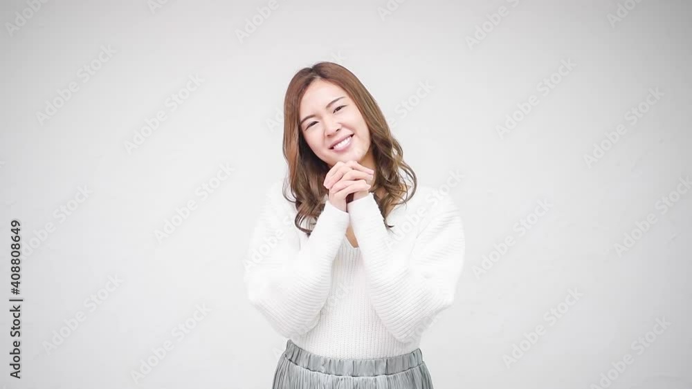 白い壁の前に立って、お願いのジェスチャーをする若い女性 白い壁の前に立って、お願いのジェスチャーをする若い女性