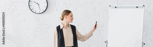 cheerful speaker looking at blank flipchart during seminar, banner