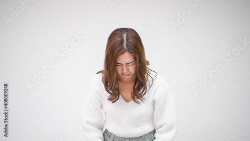 白い壁の前に立って、おじぎをする若い女性