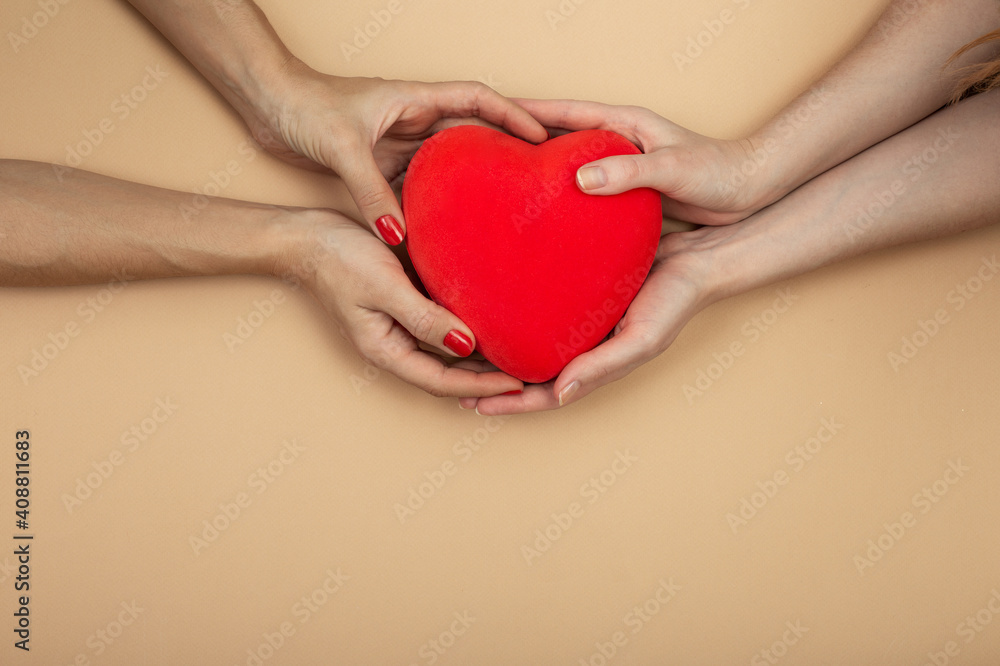 LGBT concept. Women hands holding red heart on beige background with copy space. Hands of homosexual couple on set sail champagne color. Same sex love. Lesbi Valentines card LGBT concept. Women hands holding red heart on beige background with copy space. Hands of homosexual couple on set sail champagne color. Same sex love. Lesbi Valentines card