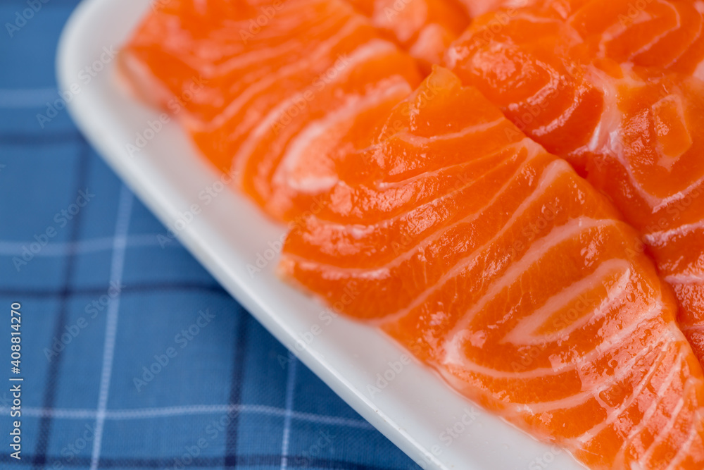 Salmon raw sashimi on whiteJapanese traditional dish on blue tablecloth. Salmon raw sashimi on whiteJapanese traditional dish on blue tablecloth.