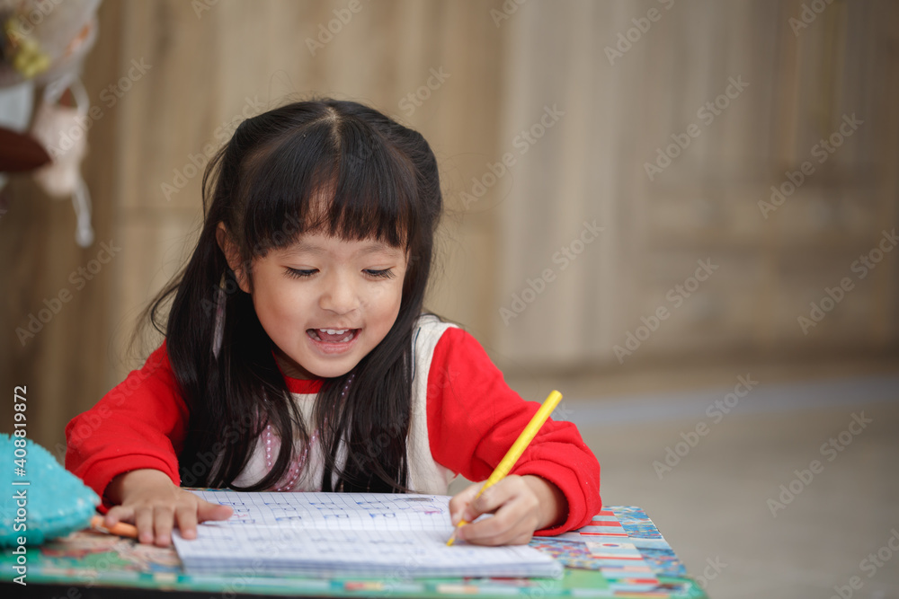 Asian little girl learning and writing in notebook with pencil Asian little girl learning and writing in notebook with pencil