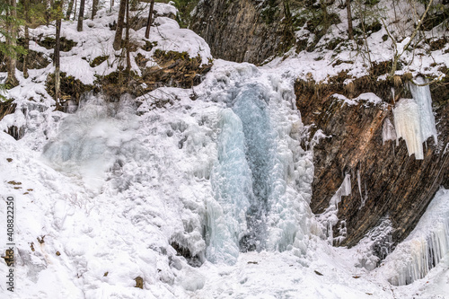 Winter forest landscape. Frozen waterfall on a stream