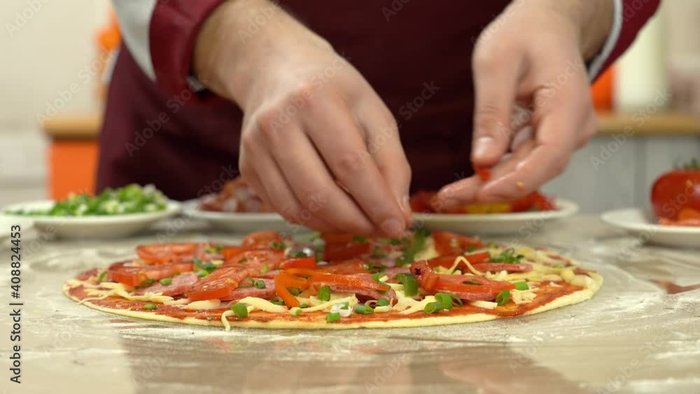 Fresh pizza dough on kitchen glossy table. Man's hand put fresh tomato on pizza dough. Fresh pizza dough on kitchen glossy table. Man's hand put fresh tomato on pizza dough.