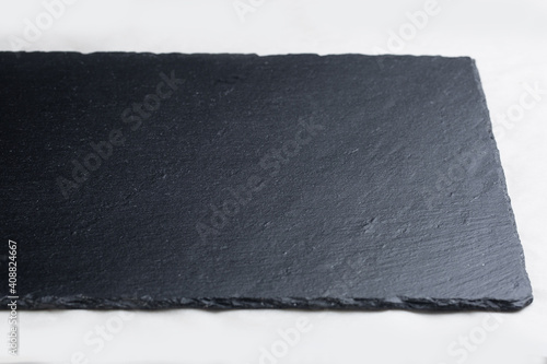 Black board on a white background. Empty black granite stone rectangular board on white textured background