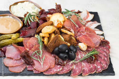 Antipasto platter with ham, prosciutto, salami, blue cheese, mozzarella and olives. Gray background. Top view. Space for text