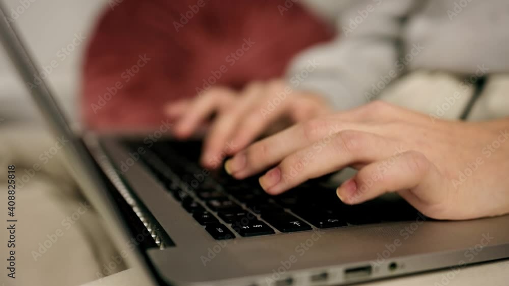 Side close view: Young woman's hands typing on laptop's keyboard during freelance work over internet from home Side close view: Young woman's hands typing on laptop's keyboard during freelance work over internet from home