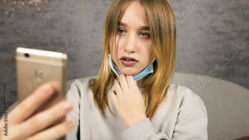 Frustated young blonde woman feeling upset using smartphone's face unlock feature wearing face mask photo