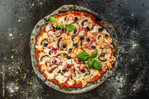 A top view of appetizing pizza with black dough and various vegetables