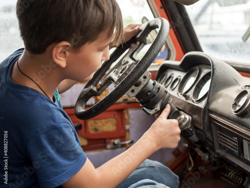 Foto An 11-year-old boy enthusiastically plays the driver behind the wheel of an old abandoned car