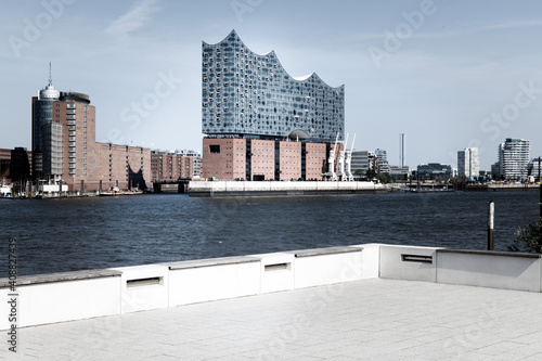 The Elbphilharmonie of the city of Hamburg seen across the river Elbe from a grey paved terrace. photo