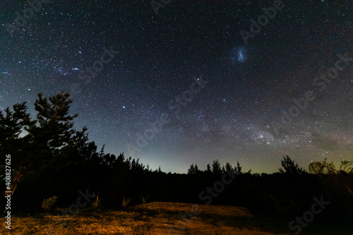 The amazing night sky full of stars. An awe scenery in the outdoors with the forest, the trees and the stars glowing in the distance. A dreamlike and colorful scenery at Puertecillo wood