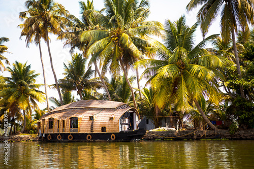 House-boat pleasure cruise ship in India, Kerala on the seaweed-covered river channels of Allapuzha in India. Boat on the lake in the bright sun and palm trees among the tropics. Sight Houseboat