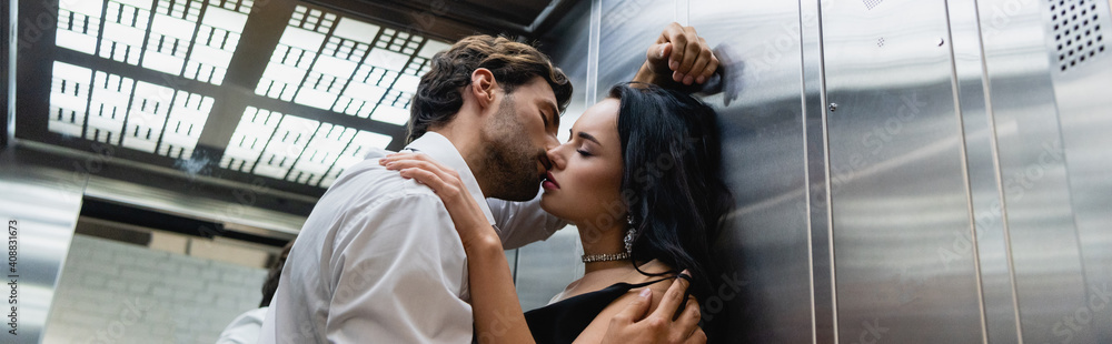 Fototapeta premium young man kissing sensual elegant woman in elevator, banner