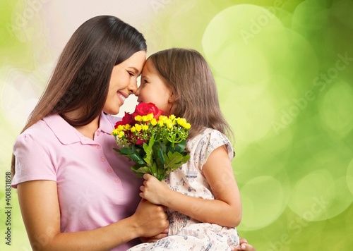 Mother and daughter with bouquet of flowers on blurred background.