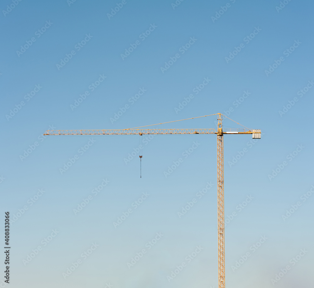 A lonely yellow tower crane on the sky background A lonely yellow tower crane on the sky background