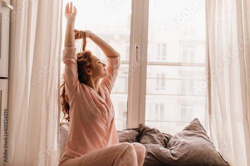 Wallpaper Mural Cute female model in pink pajama enjoying morning. Pleasant ginger woman sitting on bed. Torontodigital.ca